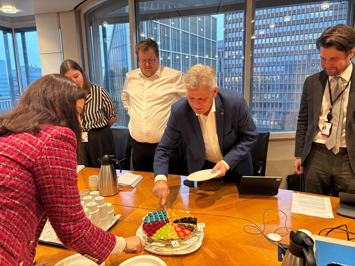 Kommunalminister Bjørnar Skjæran og Nina Solli, adm. dir. i NHO Byggenæringen spiser kake sammen med andre møtedeltakere